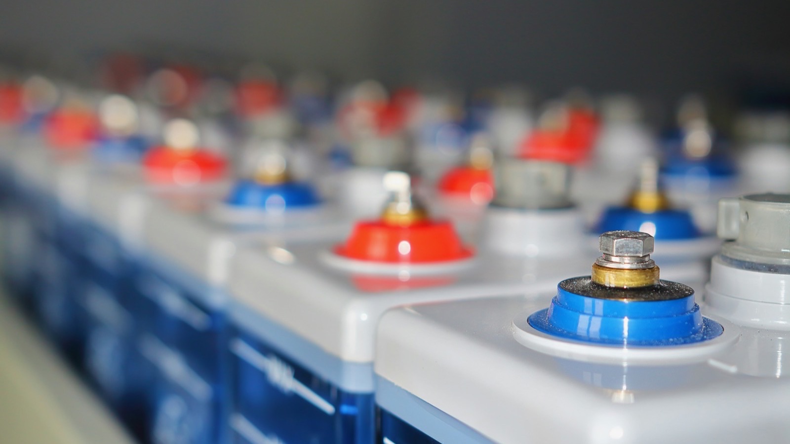 Rows of industrial battery cells with red and blue terminal caps, representing the battery shipments that travel under dangerous goods rules by air