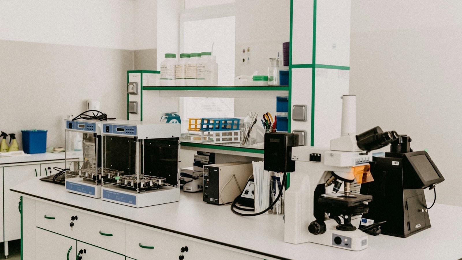 A bright laboratory workbench with a microscope and analytical testing equipment, representing the standards testing that imported goods undergo before customs release