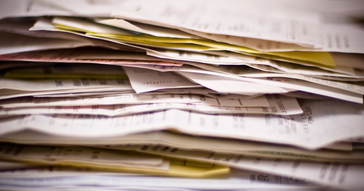 Close-up of a stack of paper documents, representing the commercial invoice and paperwork required for customs clearance