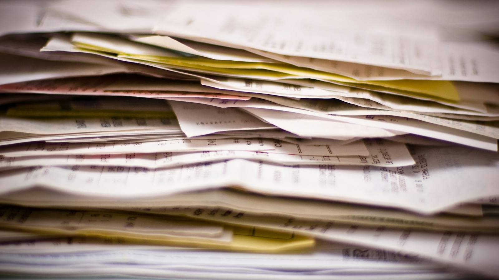 A thick stack of invoices and receipts seen close up, representing the paperwork that supports a declared customs value