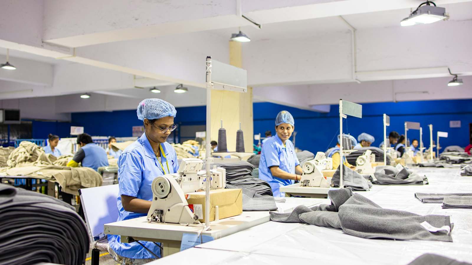 Workers at sewing machines on a garment factory production line, representing export manufacturing that uses imported inputs