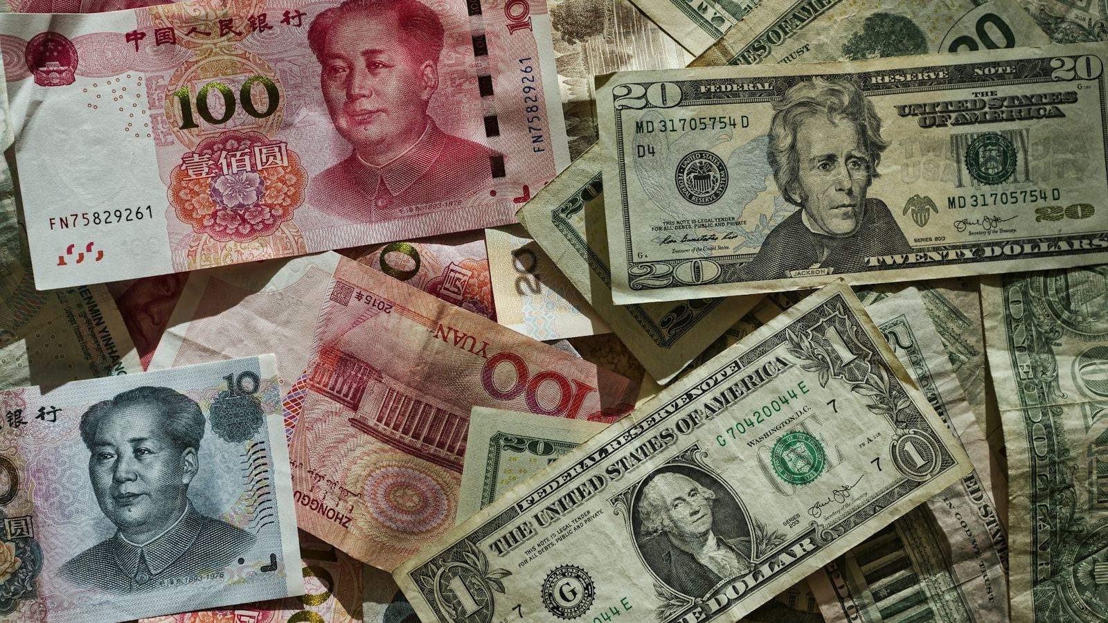 Chinese yuan and US dollar banknotes scattered and overlapping, representing the currency conversion sitting inside every China import