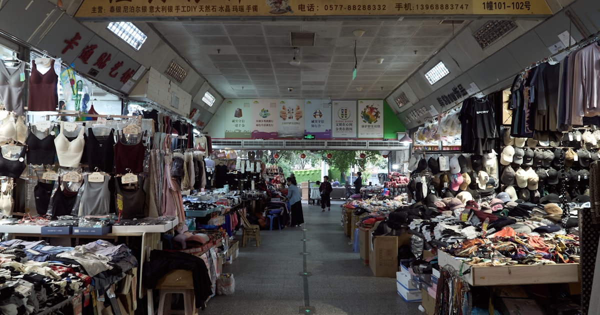 Busy indoor wholesale clothing market with rows of stalls, representing sourcing from Guangzhou's wholesale market districts
