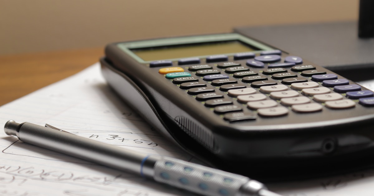Calculator and pen on paper, illustrating how to calculate your total landed cost