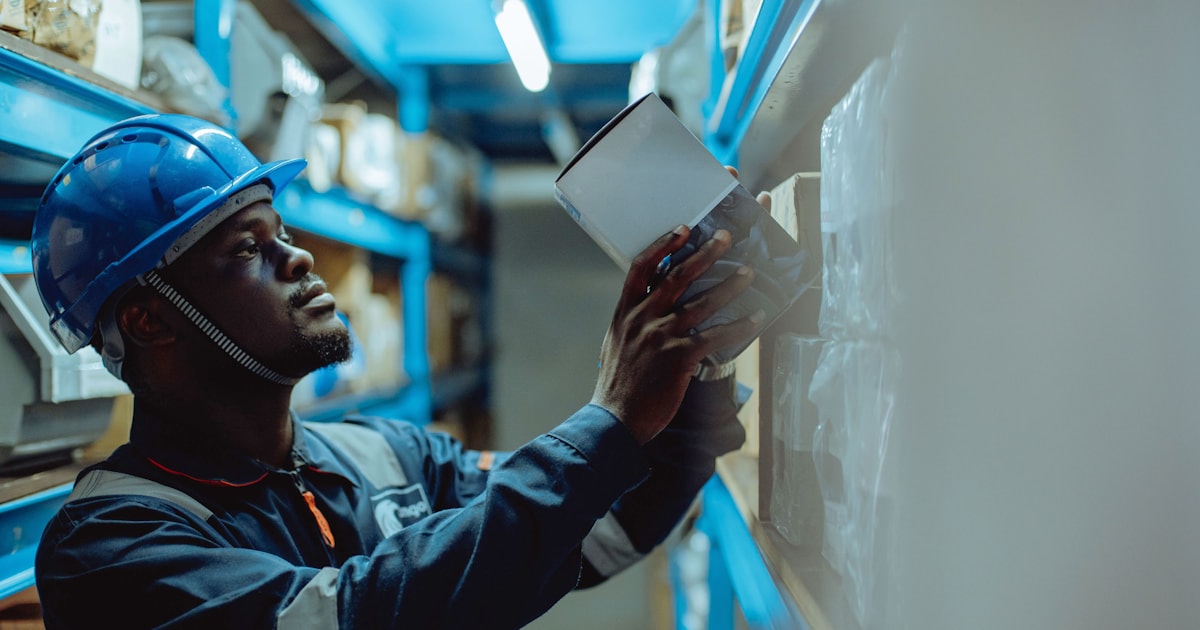 Warehouse worker in a hard hat reviewing a checklist, representing how to evaluate and choose a freight forwarder