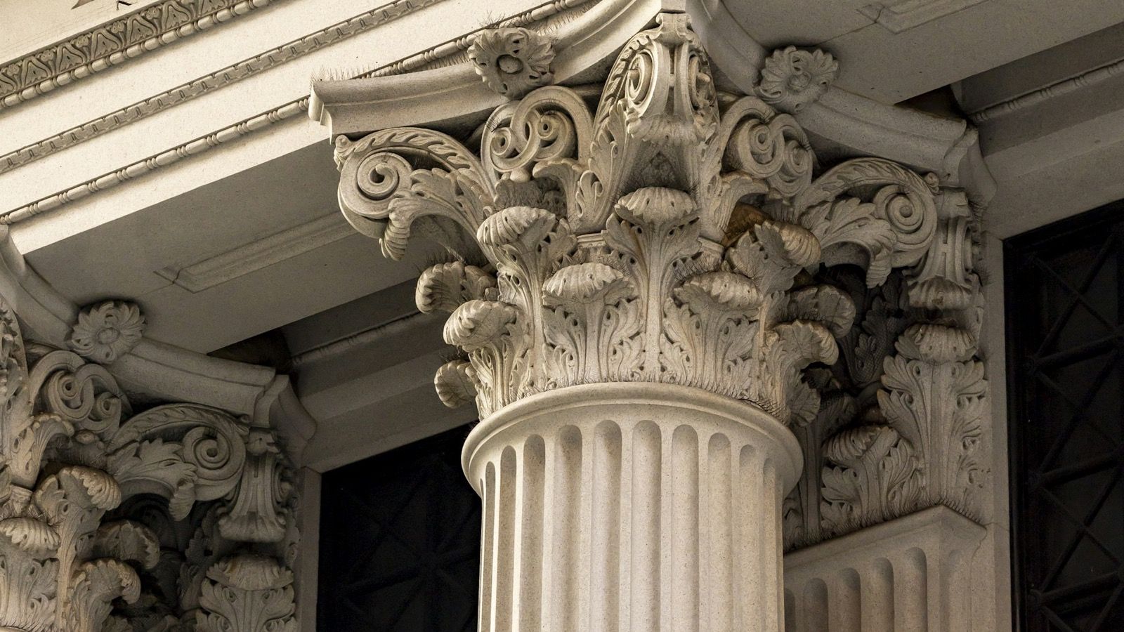 An ornate carved stone column capital on a classical bank building facade, representing the issuing bank at the centre of a letter of credit