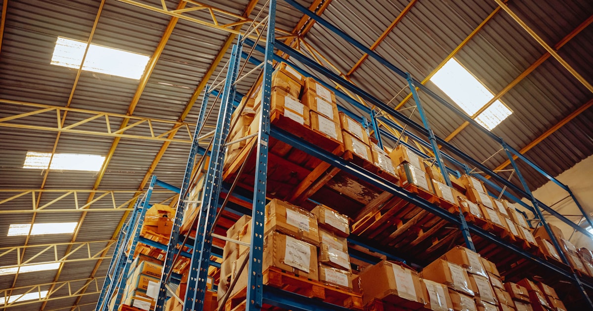 Tall warehouse shelving stacked with labeled cardboard boxes, representing what a packing list documents about a shipment's contents
