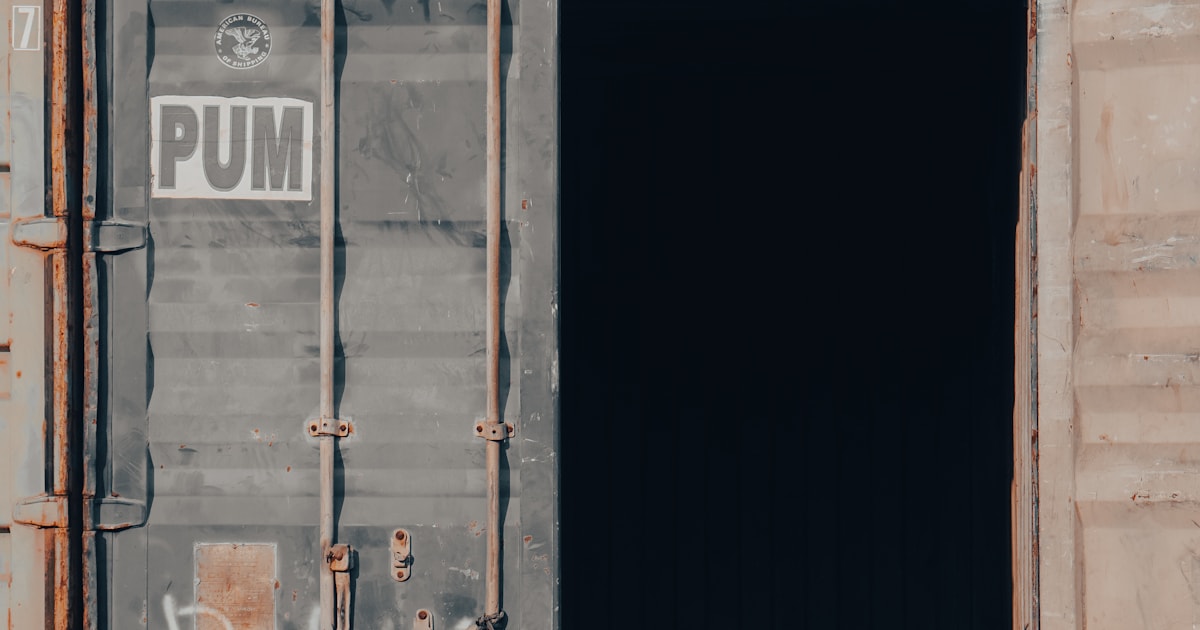 Weathered shipping container with its door open, representing a container opened for physical customs examination