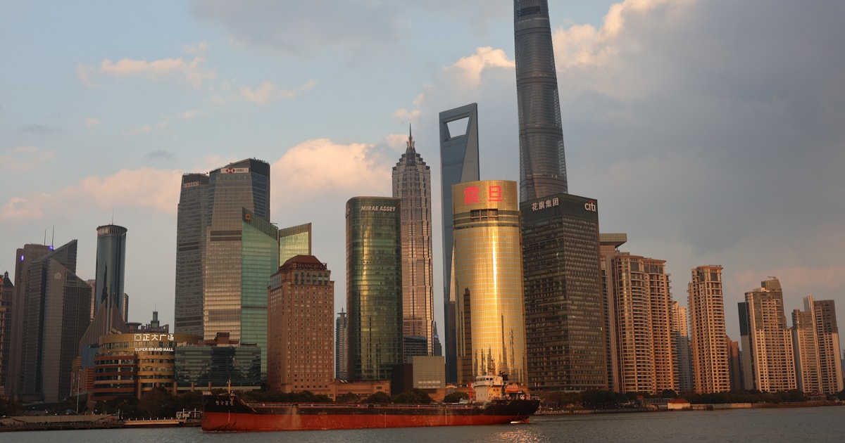 Shanghai's Pudong skyline with a cargo ship on the river, representing why Shanghai appears as the port of loading on many shipments