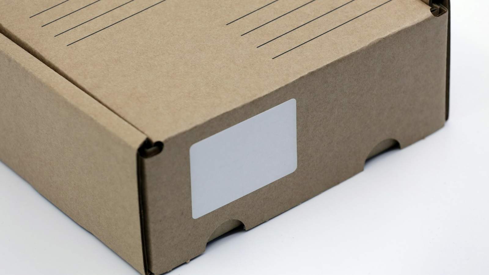 A plain brown carton with a blank white label on its side, representing the shipping marks that belong on every box