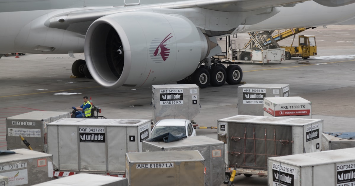 Air cargo containers being loaded onto a plane on the tarmac, representing how an Air Waybill documents an air freight shipment