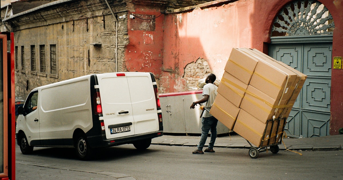 Courier unloading boxes from a delivery van, illustrating door-to-door delivery